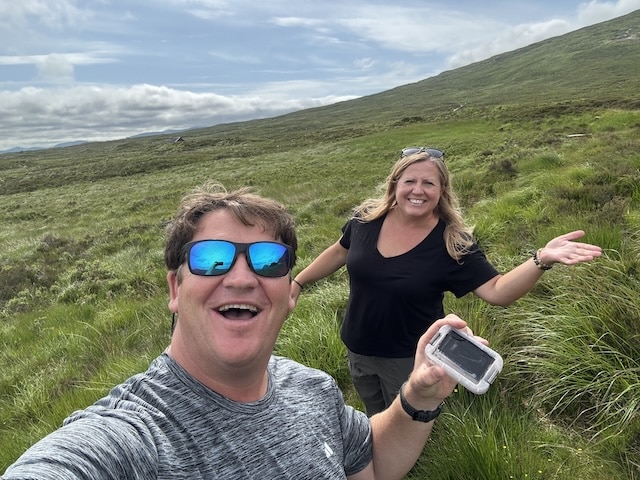 Finding a Geocache in Glencoe, Scotland summer 2026 on a beautiful sunny day with green mountains - we love Geocaching all over the world in our travels for 13+ years. 
